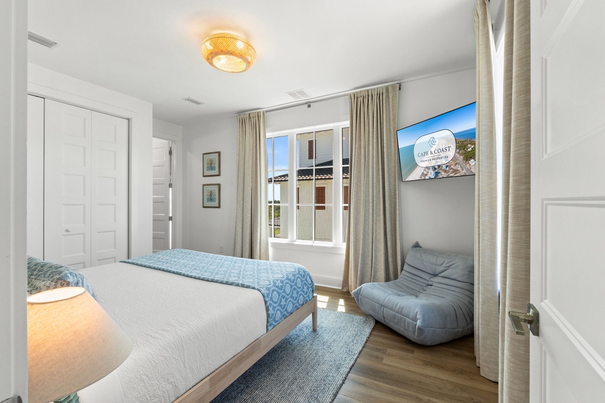 Unwind in this serene bedroom with soft linens, natural light pouring through large windows, and a cozy lounge chair perfect for your morning coffee or evening relaxation.