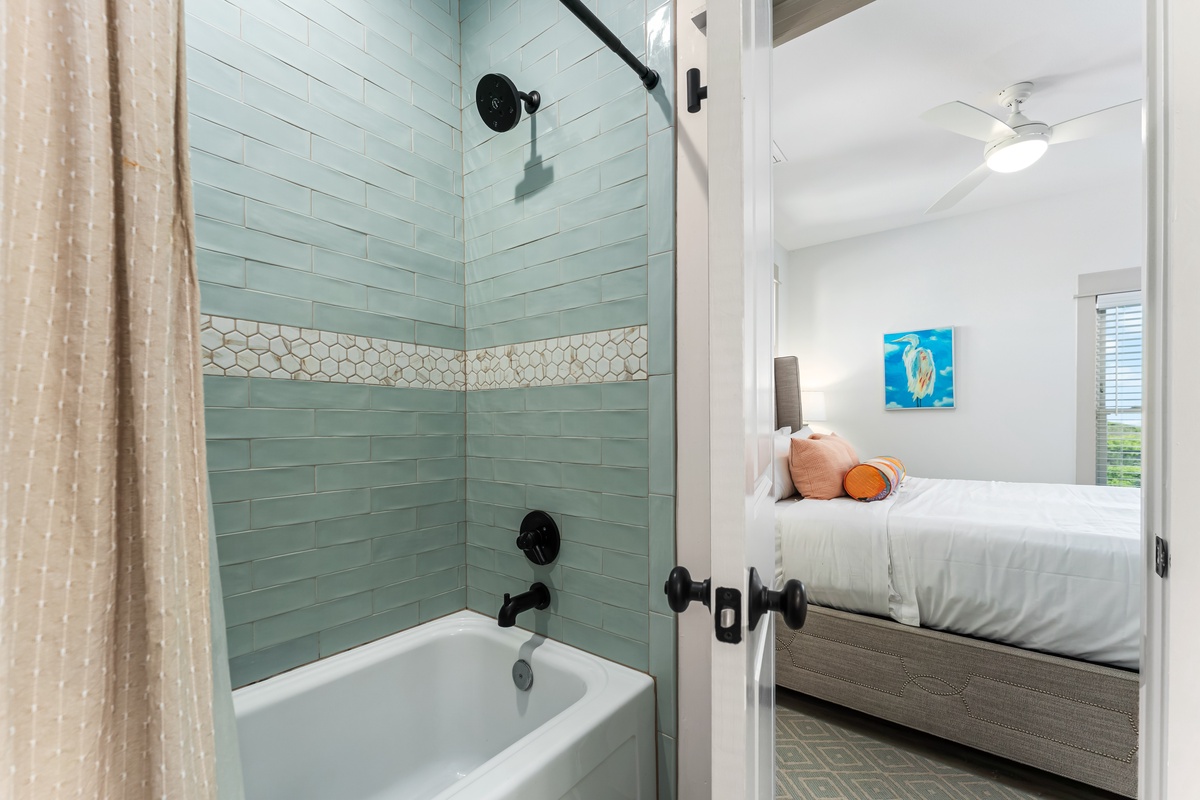Step from your cozy bedroom into this stylish bathroom with soothing seafoam tiles and a relaxing soaking tub.
