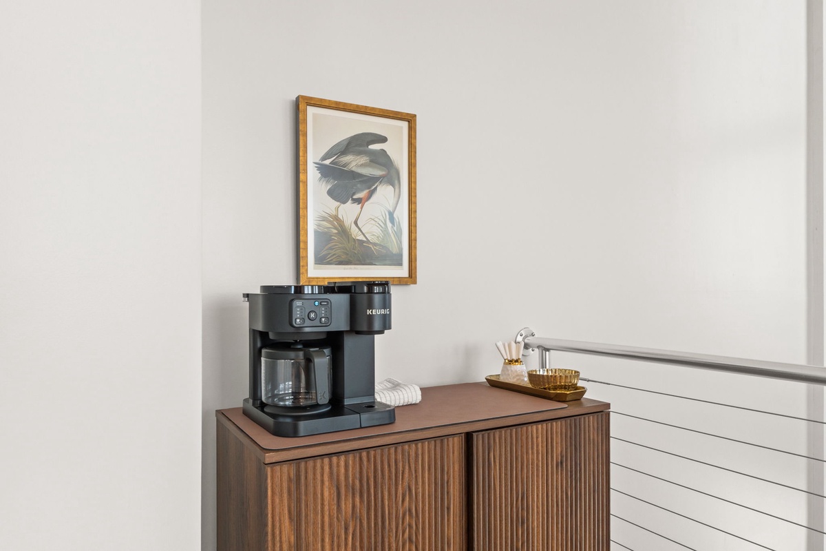 Start your mornings right with the premium coffee maker, perfectly positioned beside elegant artwork for your daily ritual.