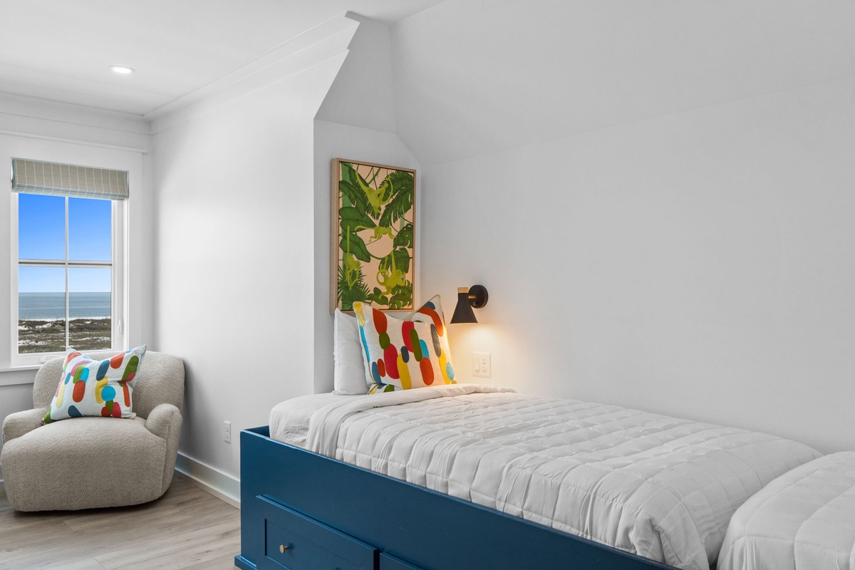 Wake up to stunning ocean views from your cozy bedroom, where coastal breezes and cheerful pops of color promise a restful getaway.