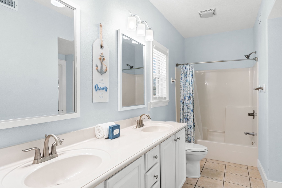 Freshen up in this coastal-themed bathroom with dual vanities and a relaxing tub-shower combo—your peaceful retreat after a day of adventure.