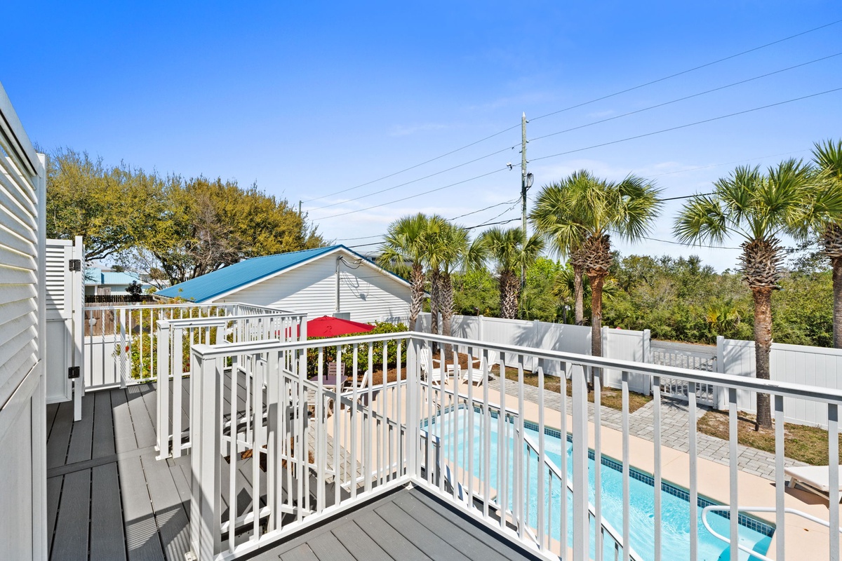 Your private balcony offers stunning pool views surrounded by swaying palm trees under brilliant blue skies.