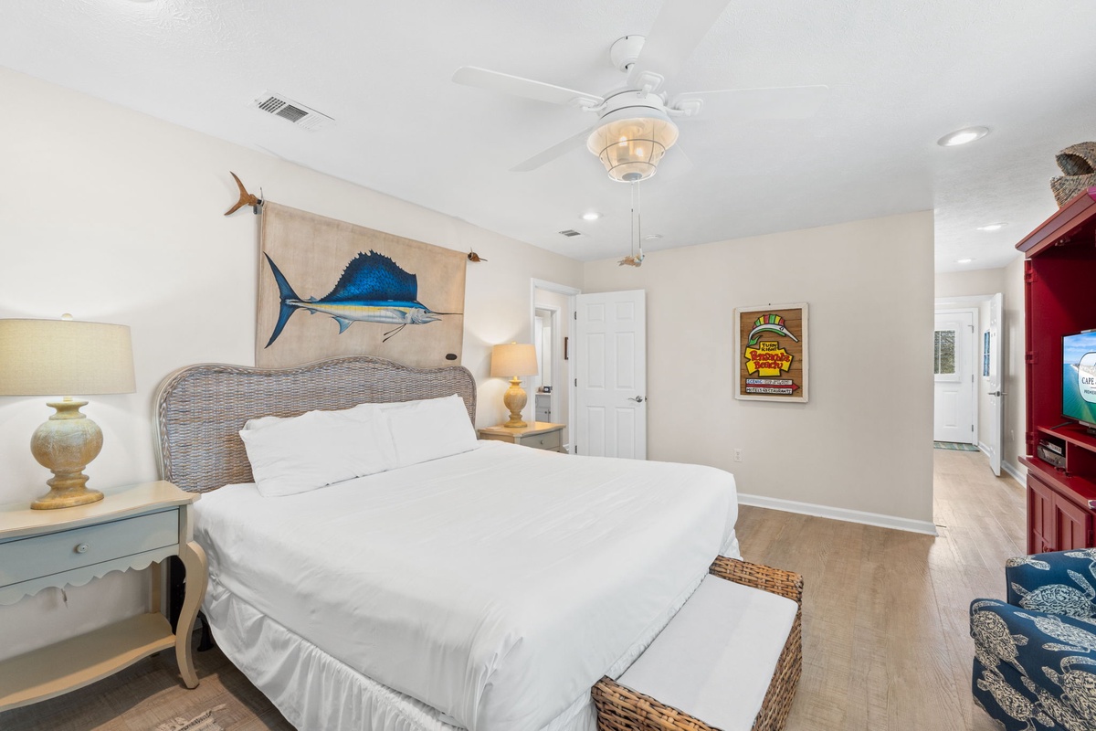 Unwind in your coastal-themed bedroom featuring crisp white linens, nautical artwork, and a ceiling fan for ultimate comfort.