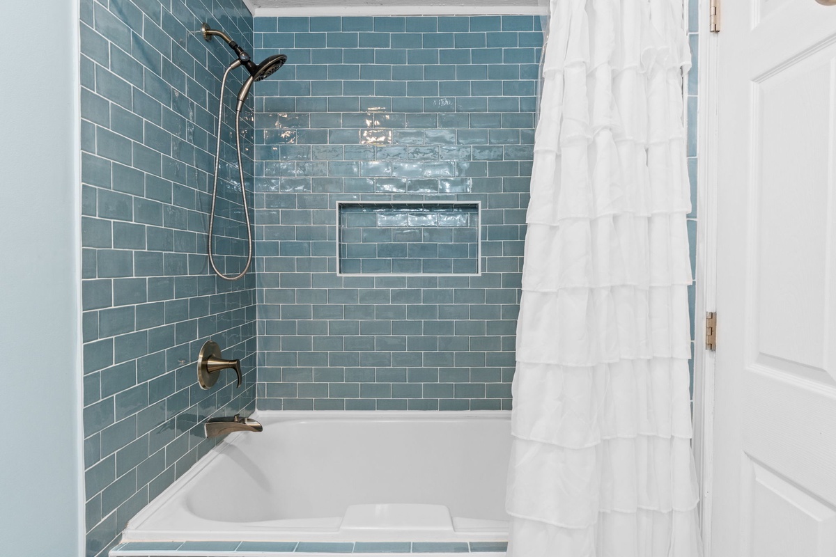 Slip into your private spa-like retreat featuring stunning blue subway tiles and a spacious tub for ultimate relaxation.