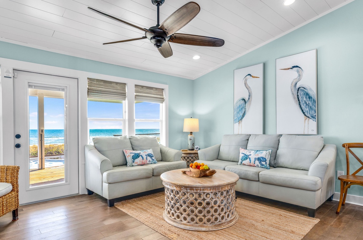 Sink into plush sofas with ocean views steps away through your private patio doors, where coastal blues and whites create your perfect beach retreat.