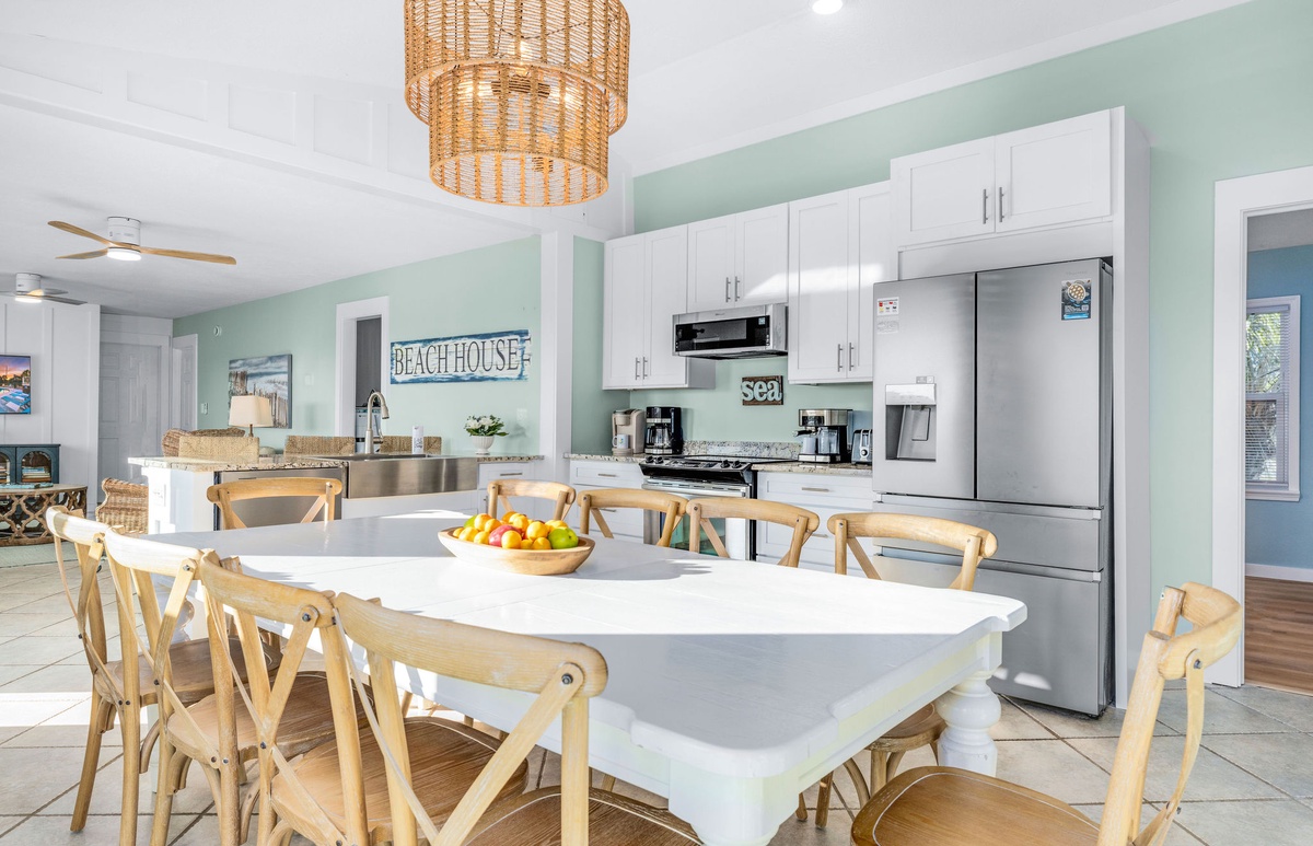 Your spacious coastal kitchen blends modern amenities with beachy charm. Fresh seafoam walls and natural wood chairs create the perfect space for family meals.