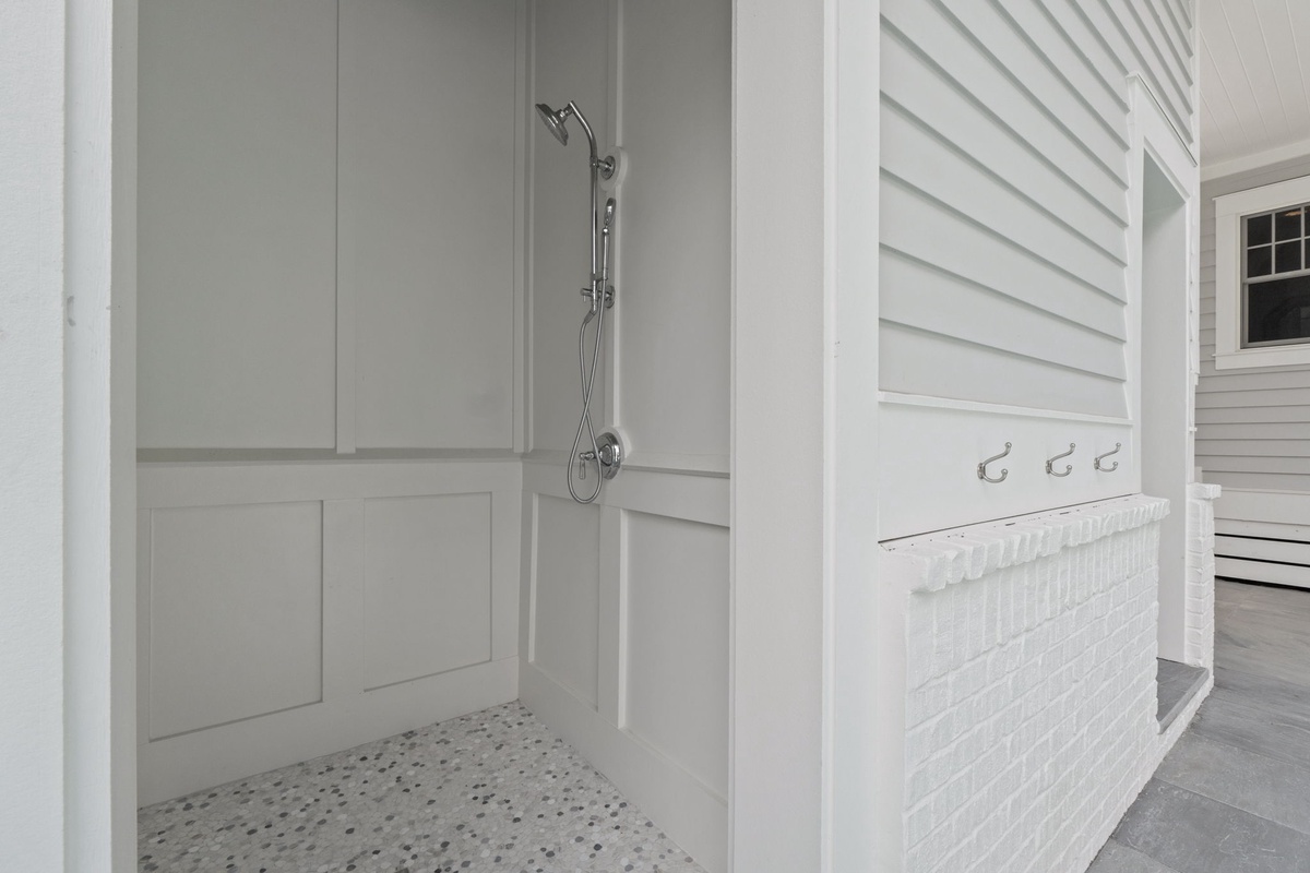 Step outside to rinse off after a day at the beach in this convenient open-air shower. Hooks and towel bar keep your essentials close at hand.