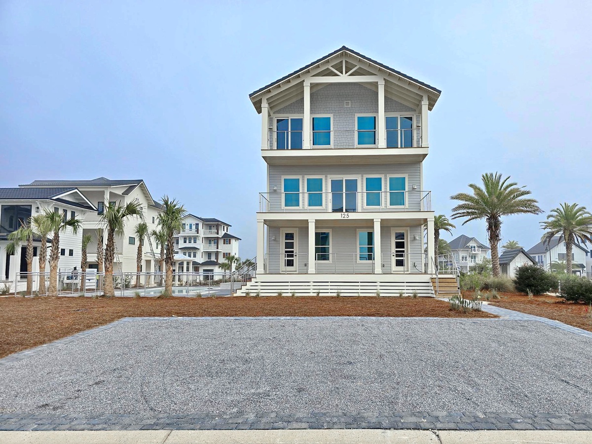 Stunning three-story coastal home featuring modern architecture and spacious outdoor decking in a scenic beachside community.
