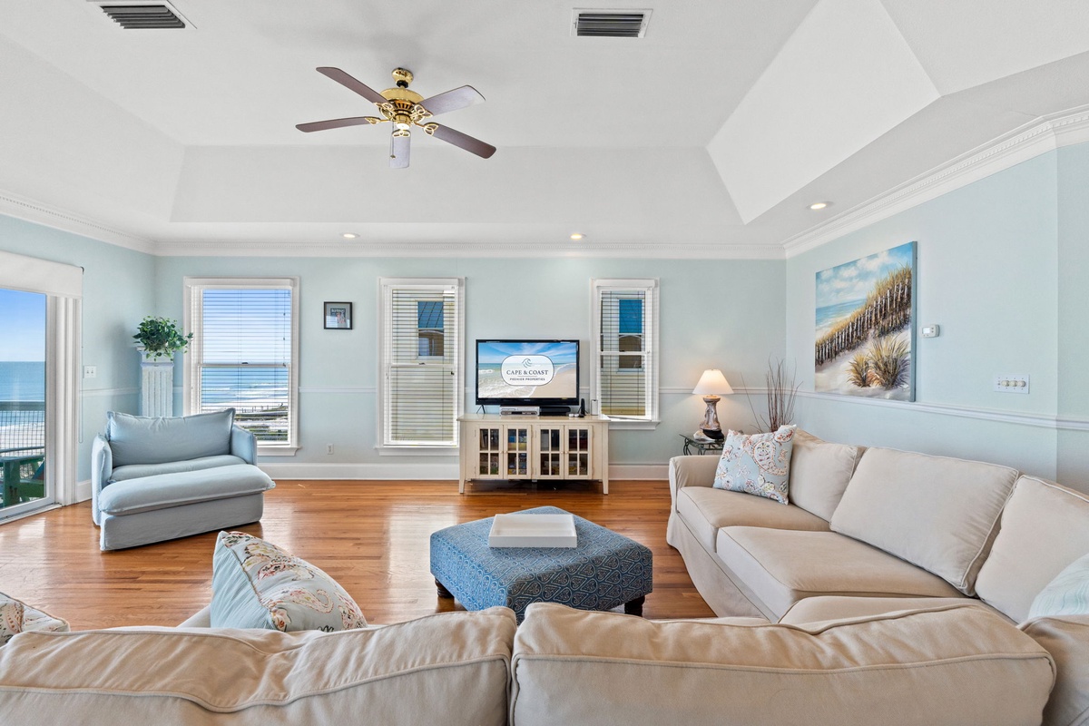 Relax in your spacious living room with coastal-inspired décor, comfortable seating, and ocean views through expansive windows.