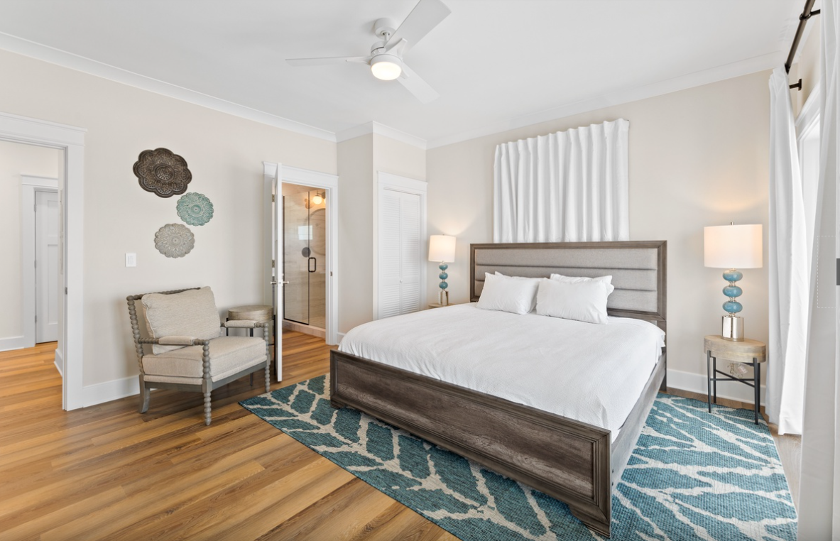 Sink into crisp white linens and unwind in your stylish bedroom, where coastal-inspired accents and warm hardwood floors create the perfect retreat.