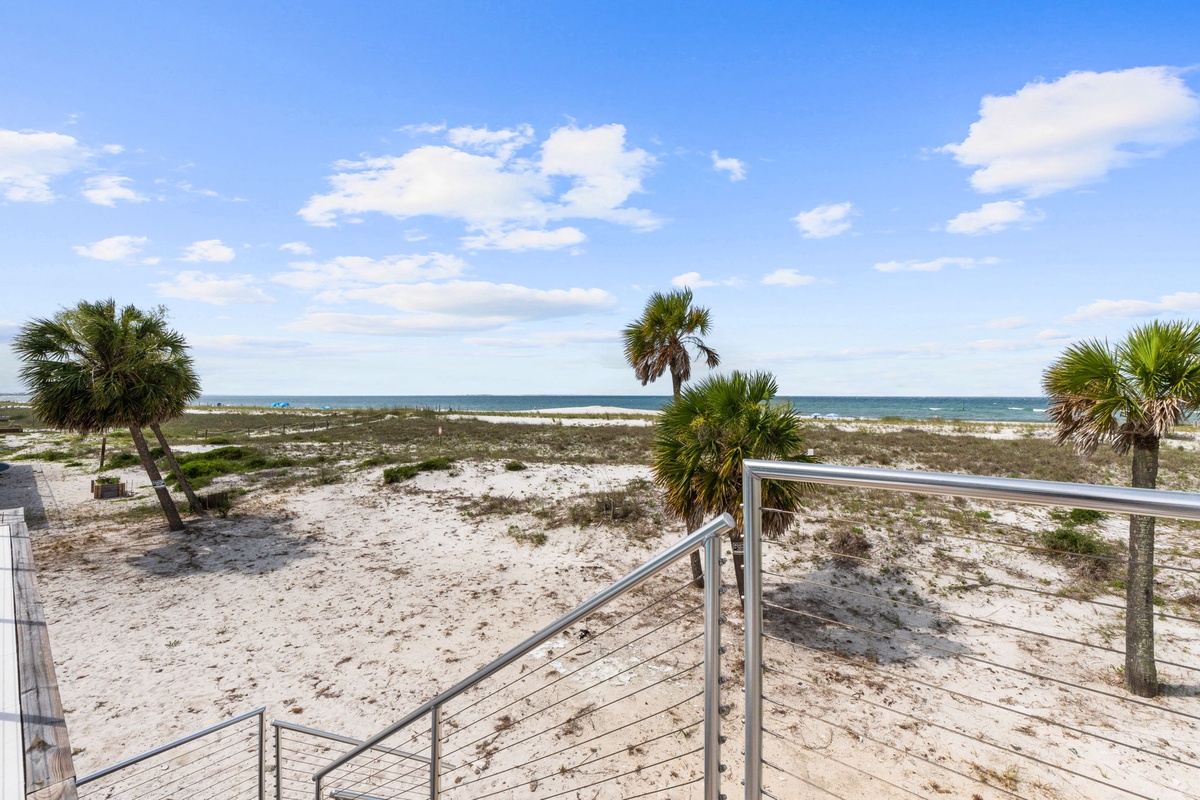 A wooden boardwalk leads you across soft white sand and swaying palms, bringing you steps away from the sparkling Gulf waves and endless coastal views.