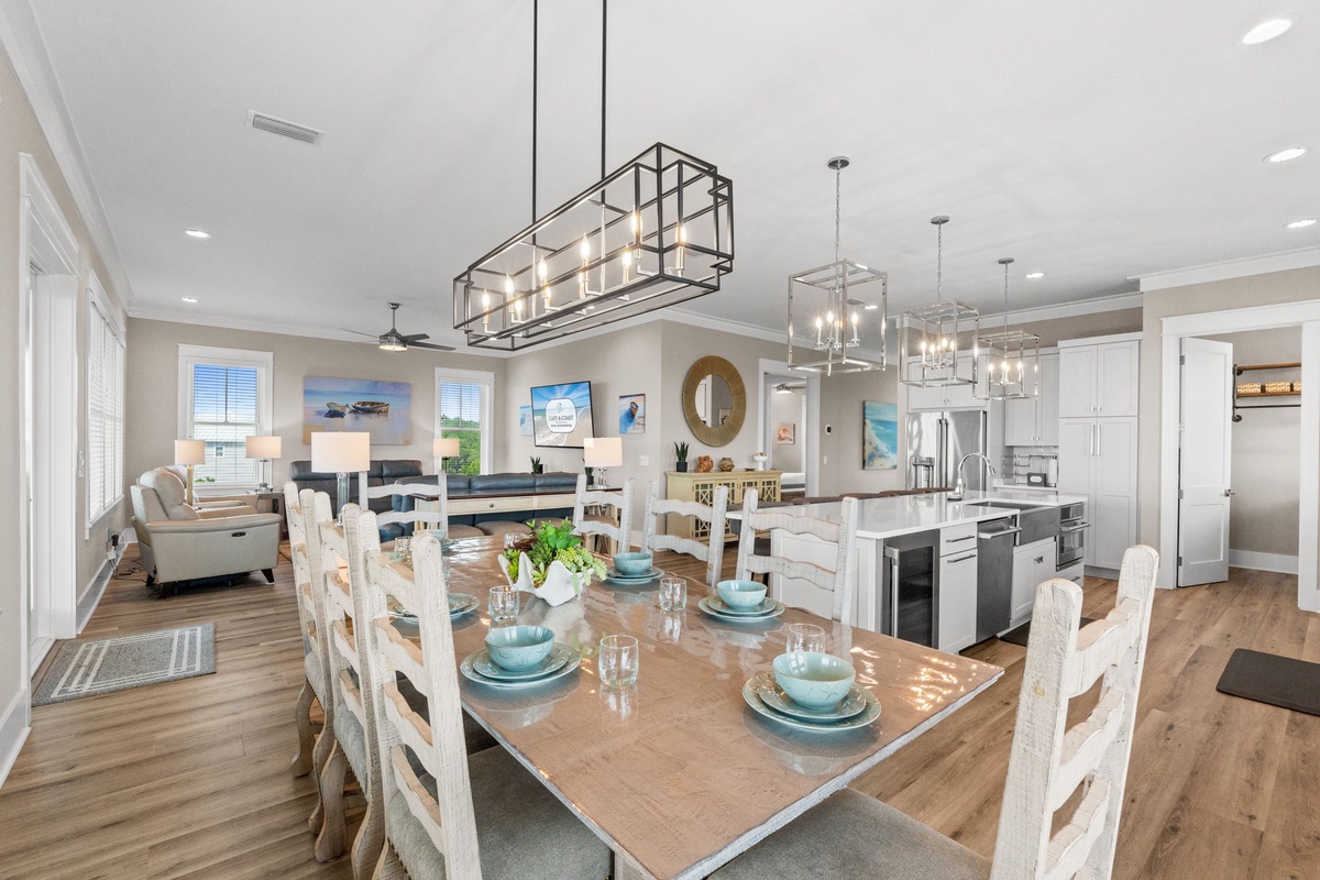 Gather around the spacious dining table where coastal charm meets modern elegance. Natural light pours in through the windows, illuminating your open-concept living space designed for memorable meals and effortless entertaining.