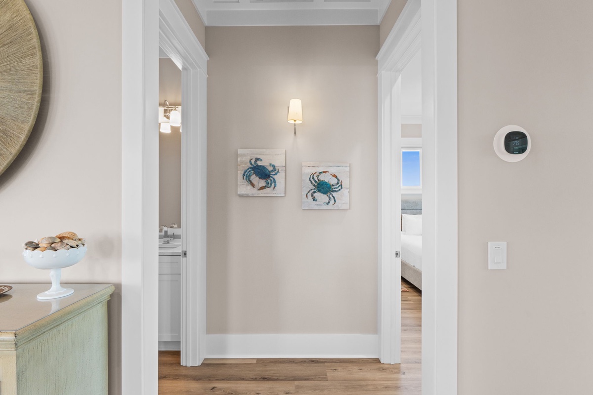 A thoughtfully designed hallway connects your bedroom and bathroom, adorned with coastal crab artwork that sets a relaxed, beachy tone throughout your stay.