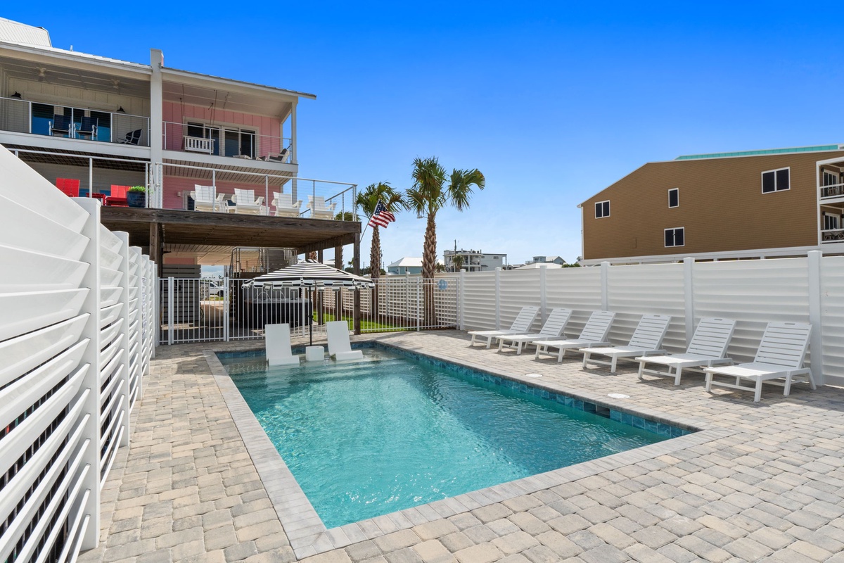 Sparkling pool surrounded by white lounge chairs and tropical palms—ideal for sunny afternoons and warm coastal breezes.