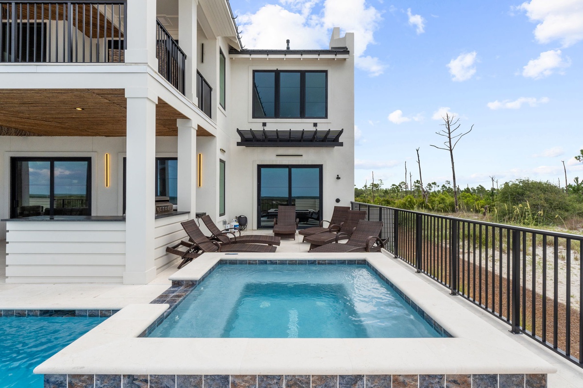 Modern coastal retreat set among natural surroundings, featuring a private pool, tiered balconies, and tranquil views of lush native vegetation along the shoreline.