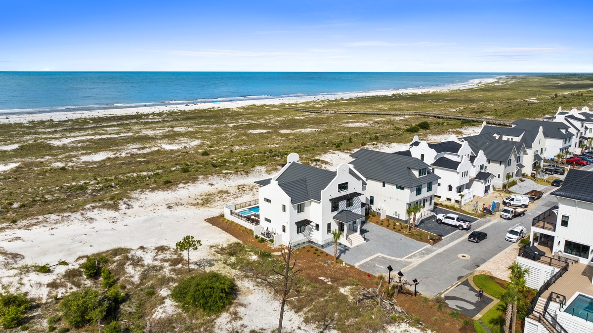 A stunning beachfront community with contemporary homes nestled along pristine white sand dunes, offering direct access to turquoise waters and expansive coastal views.