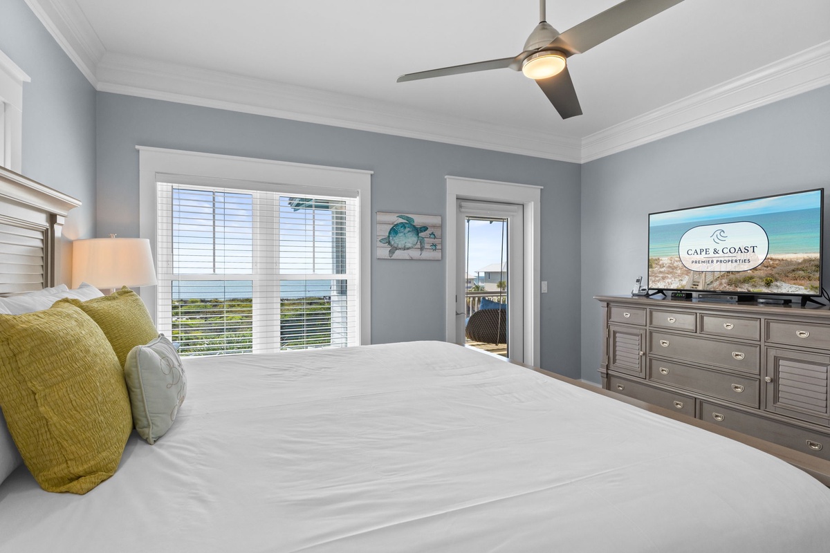 Your serene master bedroom features comfortable bedding and ocean views through bright windows for peaceful seaside mornings.