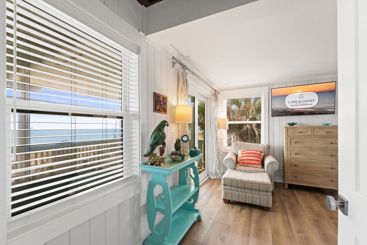Settle into your cozy sitting area with beach-cottage charm and let soft natural light warm your space. The turquoise accent table and plush armchair invite you to relax after a day exploring the coast.