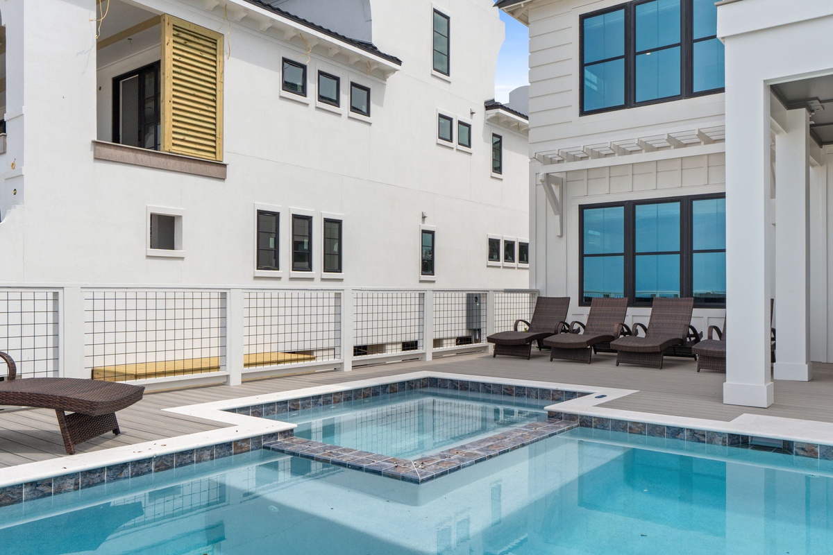 Private courtyard pool with hot tub, surrounded by modern architecture. Lounge chairs set the stage for sun-soaked relaxation in this secluded outdoor retreat.