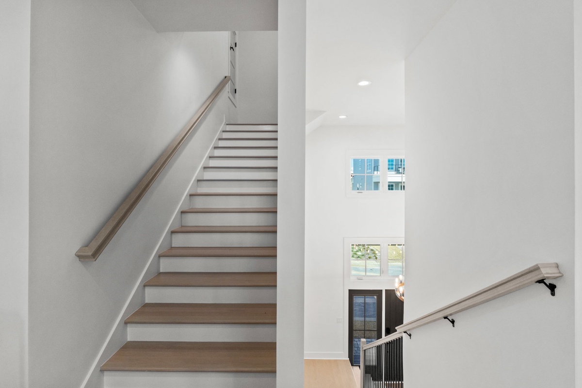 Bright, modern stairway connects your multi-level retreat with sleek wood steps and clean white walls creating an airy, welcoming atmosphere.