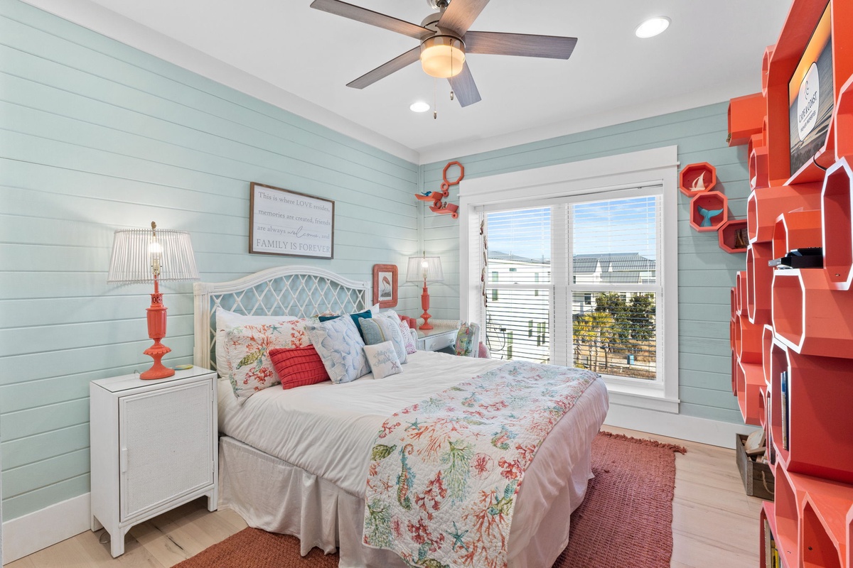 Drift off in your bright bedroom with cozy coral accents, ceiling fan, and peaceful views through French doors.