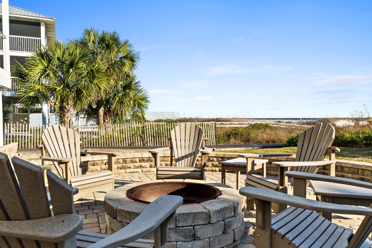 Oceanfront patio with fire pit surrounded by Adirondack chairs offering beach views and coastal breezes.