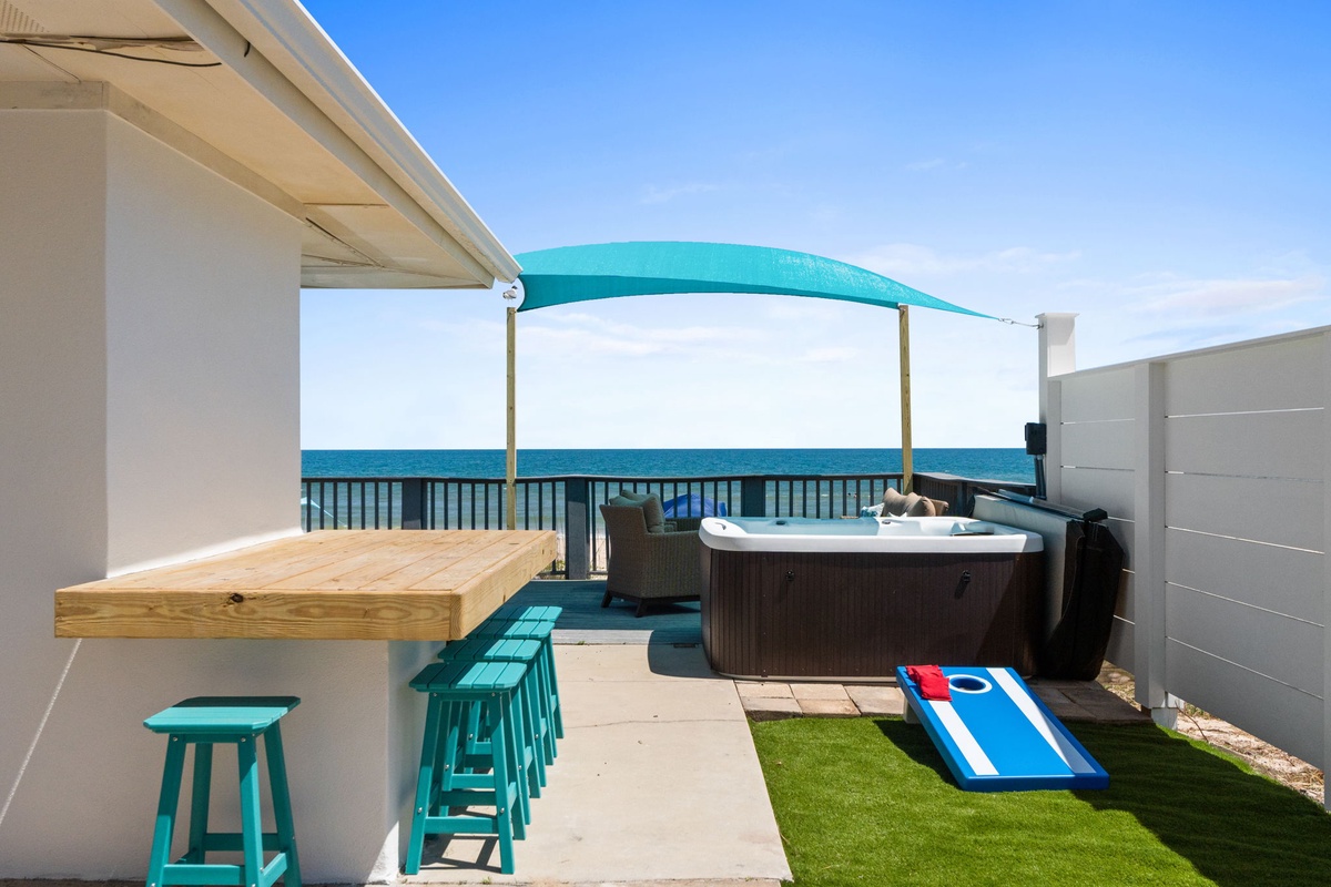 The rooftop terrace overlooks the ocean, offering direct sea views, an outdoor hot tub, bar seating, and lawn games just steps from the water.