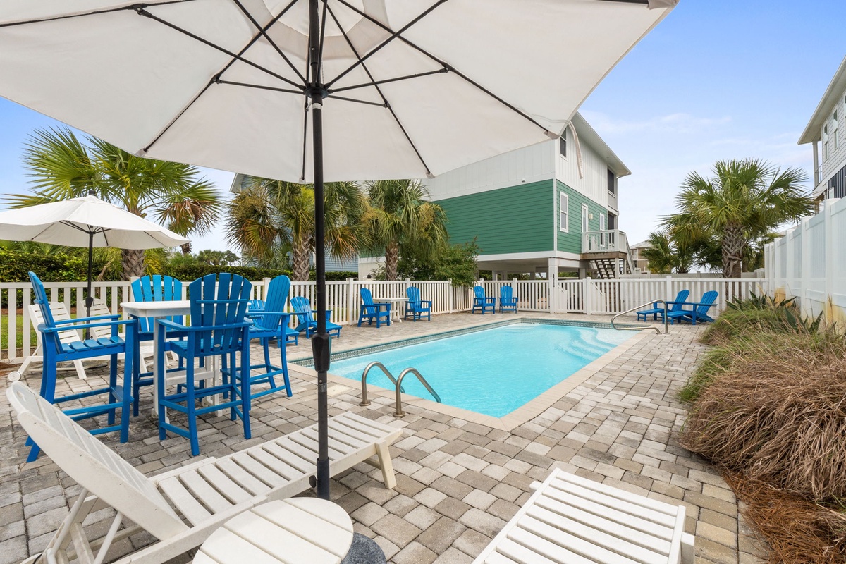 Unwind poolside under swaying palms and bright umbrellas, where vibrant blue chairs and lounge seating invite you to soak up the sun in a tranquil, tropical retreat.