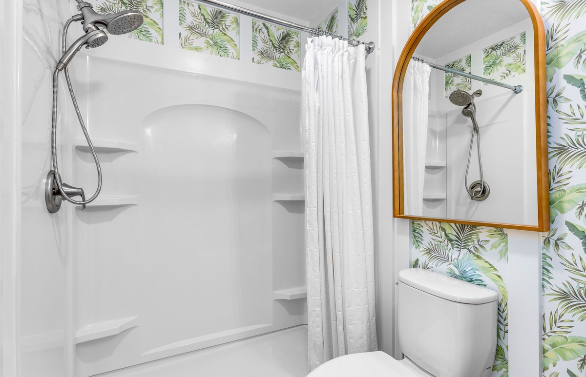 Refresh in your tropical-inspired bathroom featuring a spacious shower with modern fixtures and botanical wallpaper that brings nature indoors.