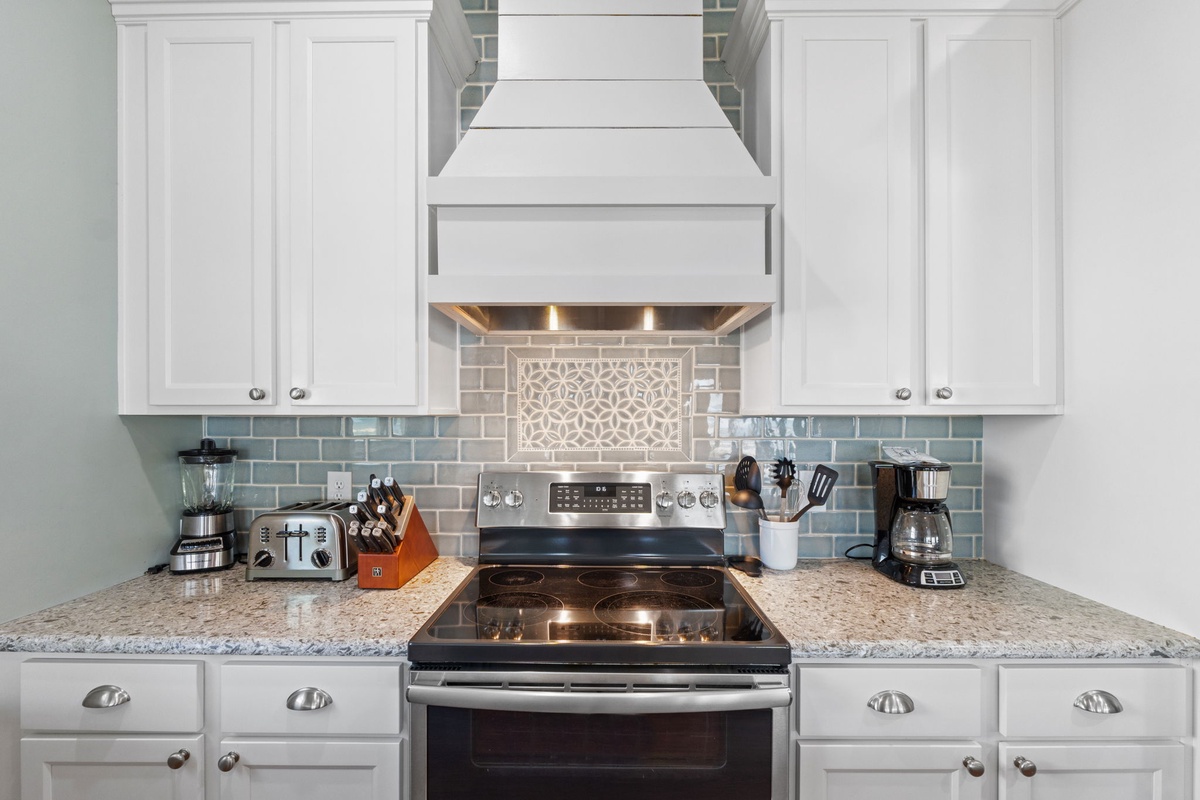 Prepare your favorite meals in this stylish, fully-equipped kitchen featuring modern appliances, ample counter space, and a beautiful tile backsplash to inspire your culinary creativity.