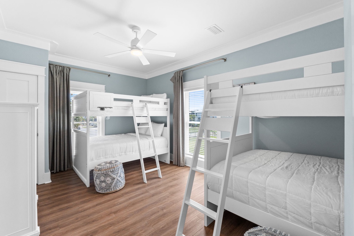 Picture your family settling into this coastal bedroom with two cozy bunk beds and ocean views through the windows. The soft blue walls and ceiling fan create a calming retreat.