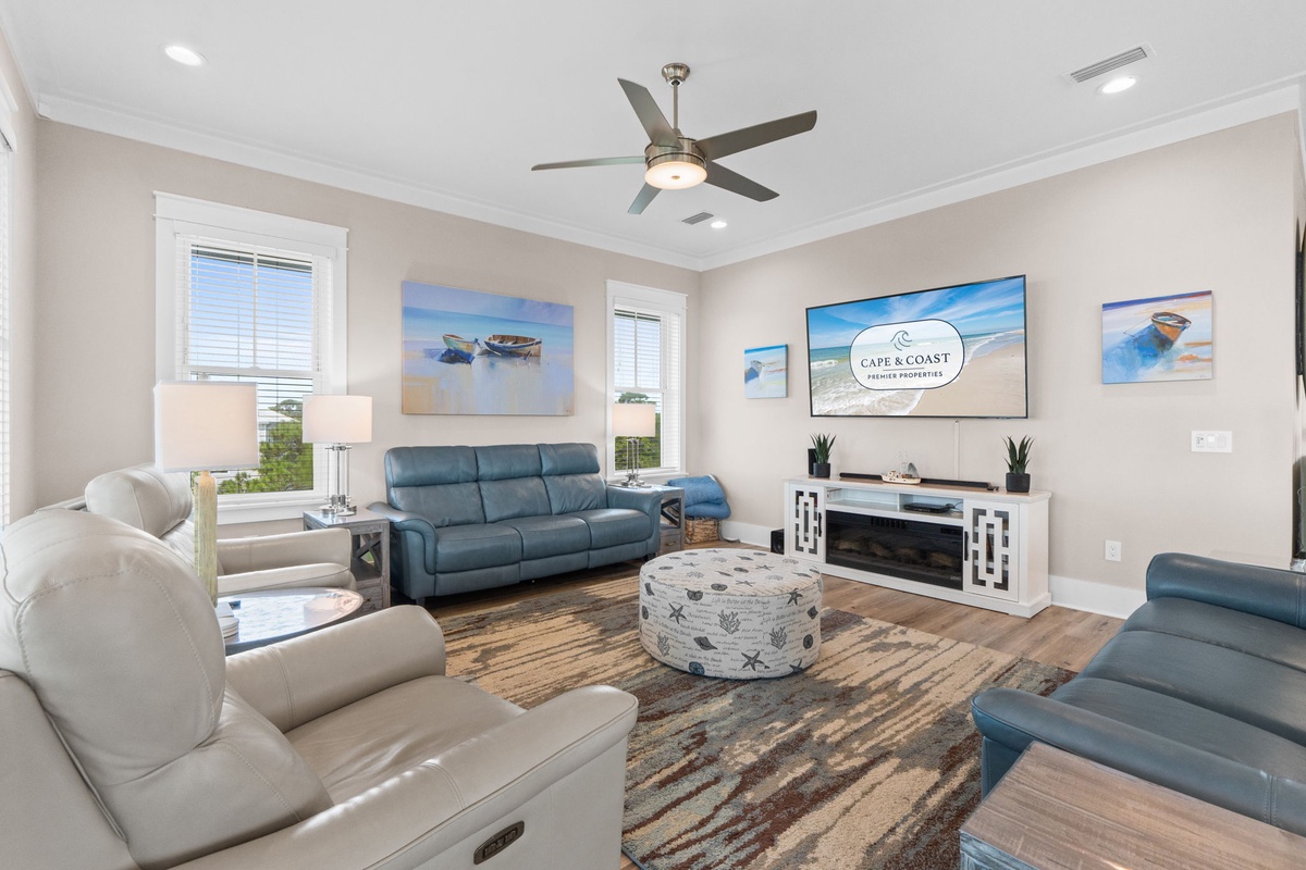 Settle into your coastal retreat, where soft neutral tones and beach-inspired art create a tranquil escape. Natural light streams through shuttered windows as you relax in plush seating beneath the gentle whirl of the ceiling fan.