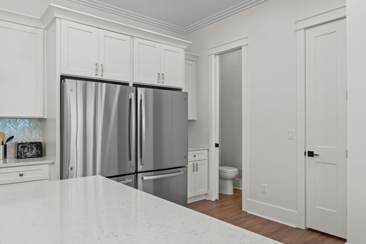 Your fully equipped kitchen features crisp white cabinetry, stainless steel appliances, and gleaming countertops—perfect for preparing meals or morning coffee during your stay.