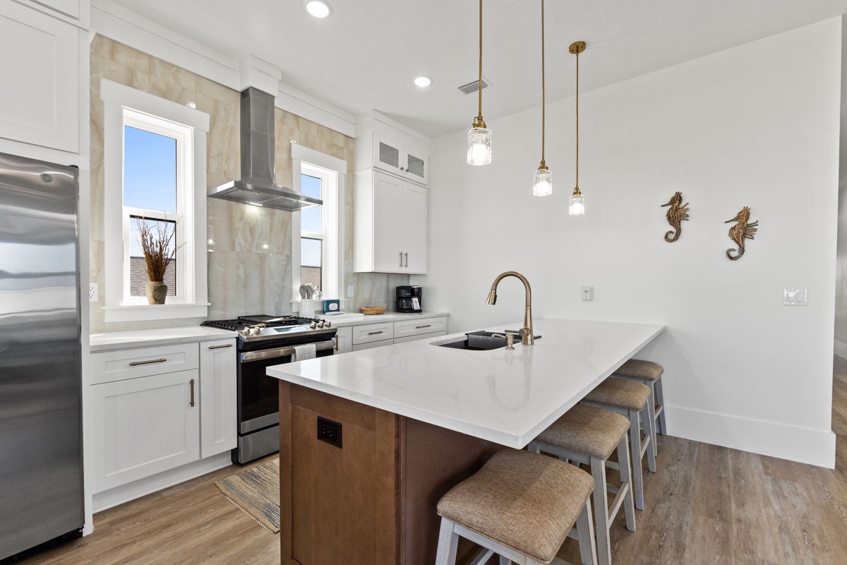 Prepare meals in your pristine white kitchen featuring sleek quartz counters, pendant lighting, and everything you need for culinary adventures.