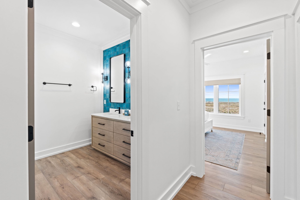 Step into your private master suite hallway connecting stunning bathroom with turquoise accent tiles to serene bedroom overlooking desert landscapes.