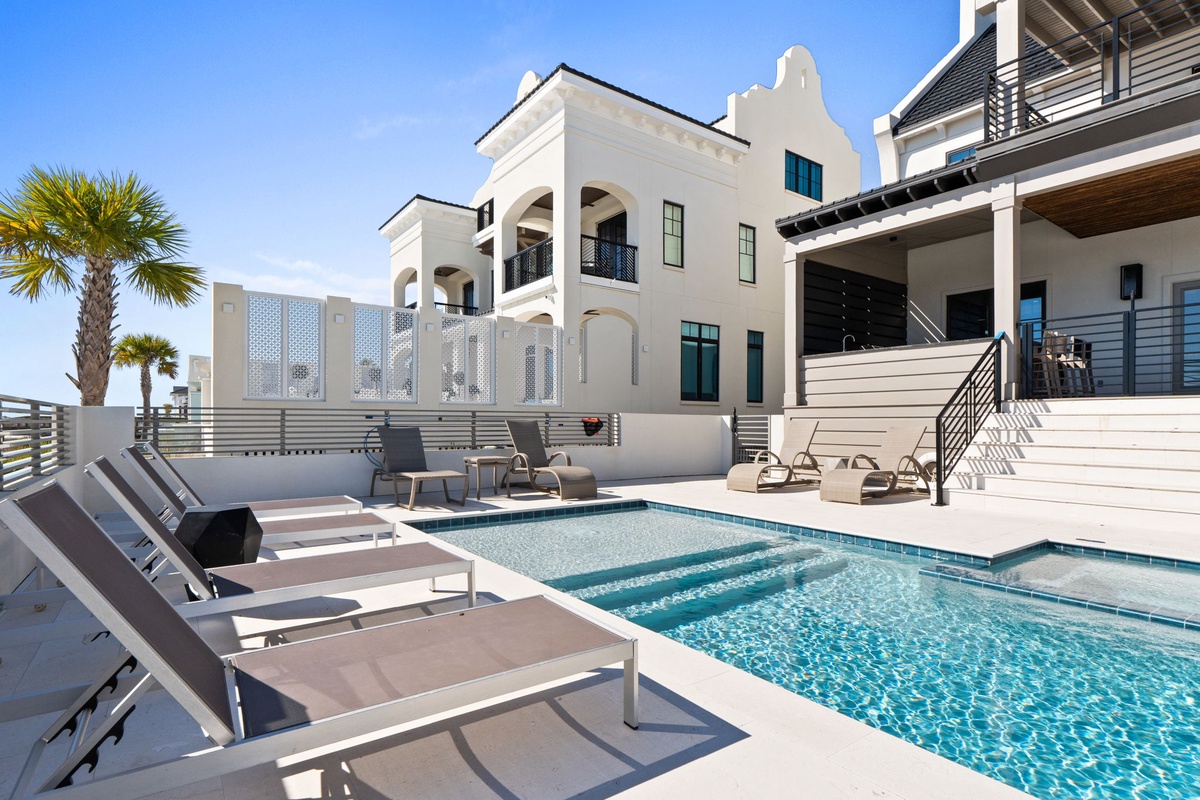 Luxurious beachfront property featuring elegant architecture, sparkling pool, and comfortable outdoor lounging areas.