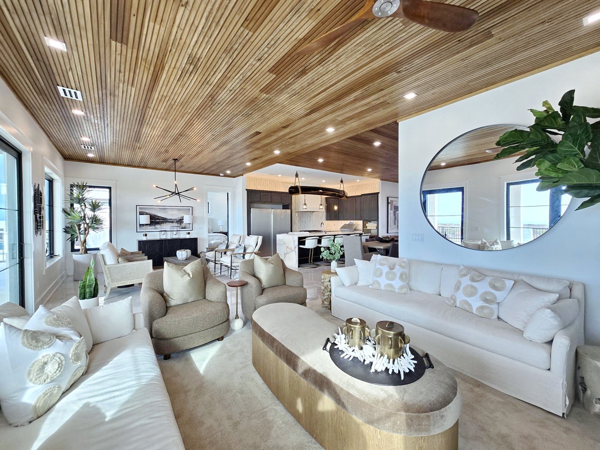 Relax in your stunning open-concept living space with soaring wood ceilings, designer furnishings, and seamless flow to the modern kitchen.