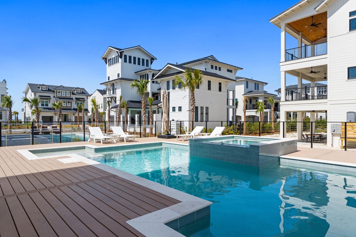 Modern coastal community featuring contemporary beach houses with palm trees and a pristine shared pool area.