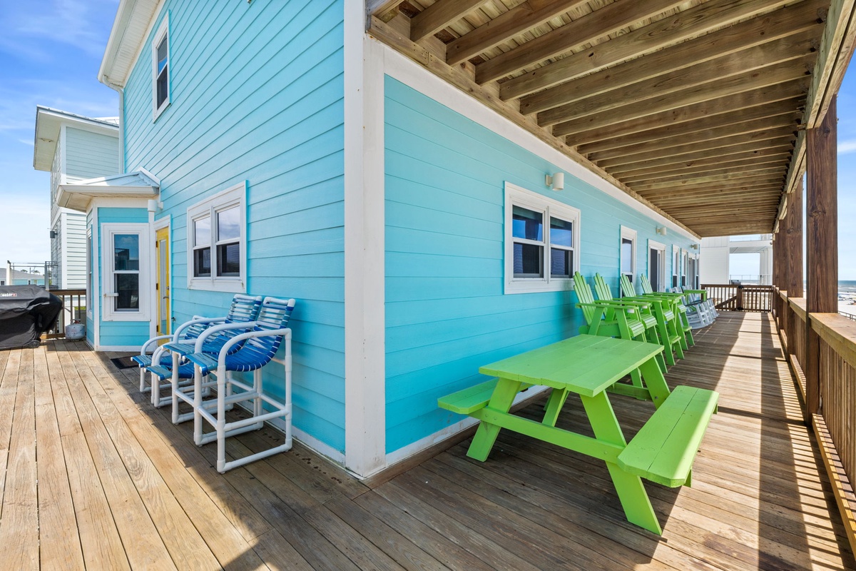 Bright coastal deck with cheerful picnic seating and shaded lounge chairs, perfect for your beachside meals and relaxation steps from the sand.