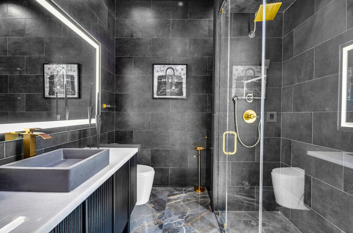 Step into your luxurious ensuite with elegant dark tiles, rainfall shower, and striking gold accents for an indulgent bathing experience.