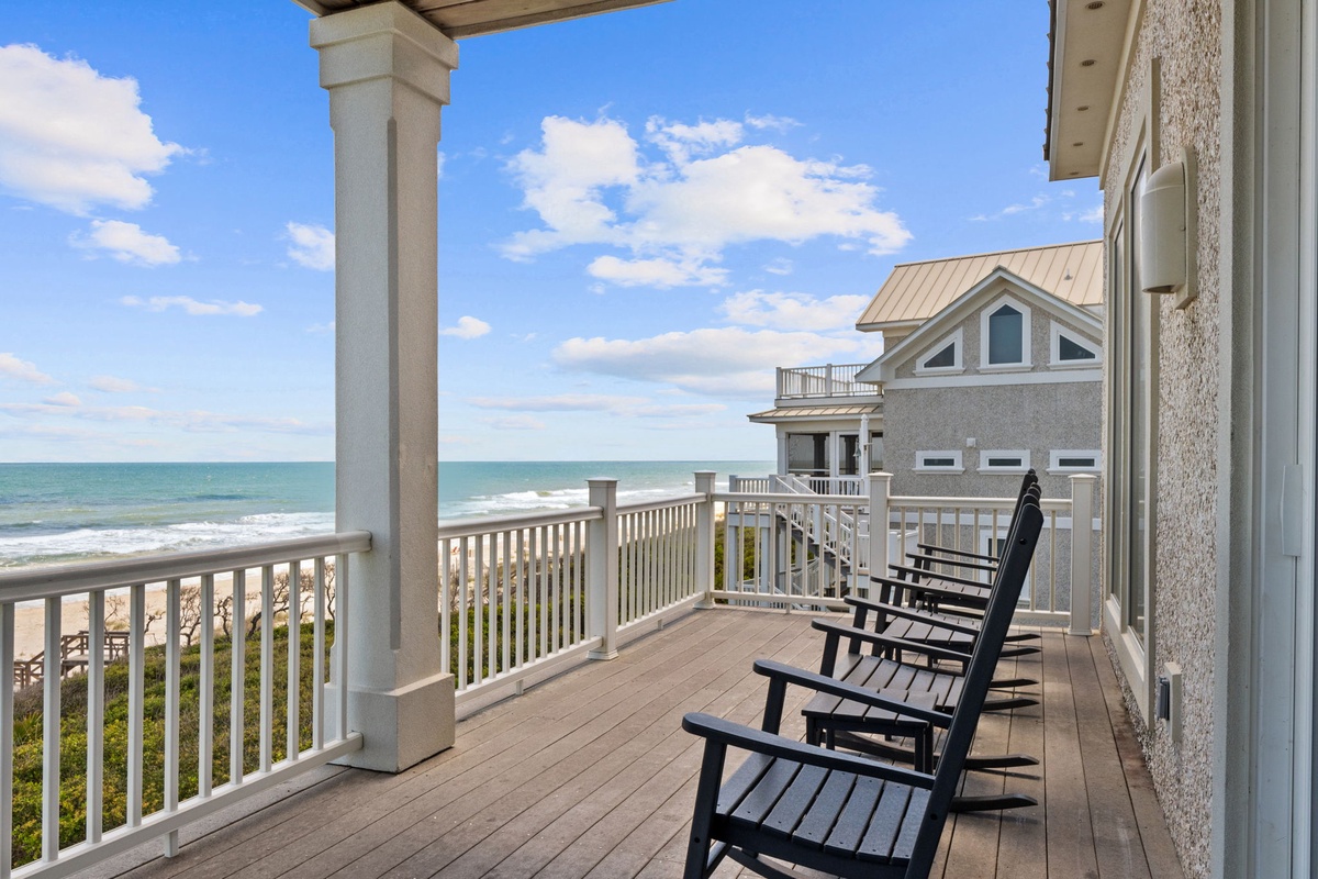 Beachfront property featuring elevated balcony with unobstructed ocean views, neighboring coastal homes, and easy beach access via shared boardwalk.