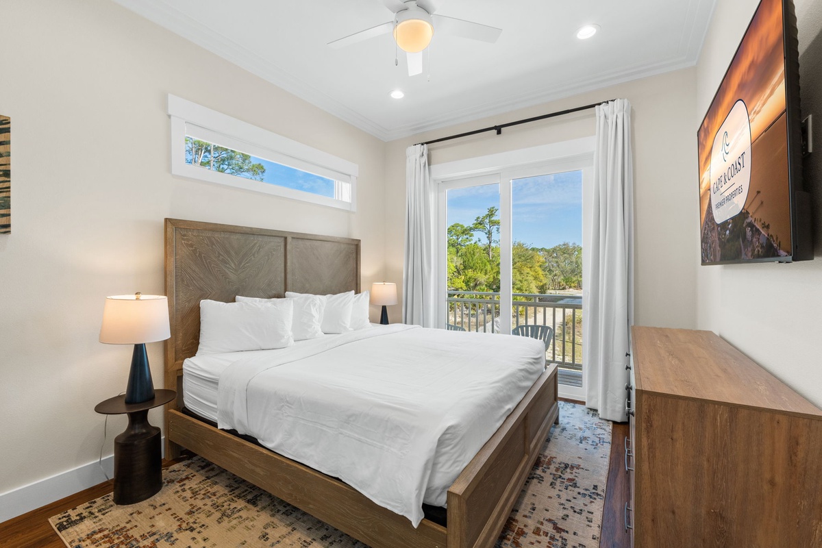 Wake up to natural light streaming through your windows in this peaceful bedroom featuring crisp linens and serene tree views from your private balcony.