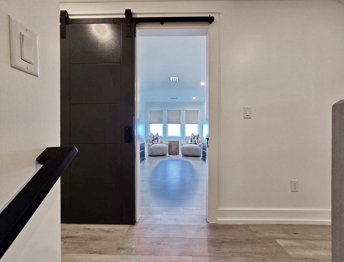 Step through this stylish barn door into your cozy living space, where comfortable seating awaits by bright windows.