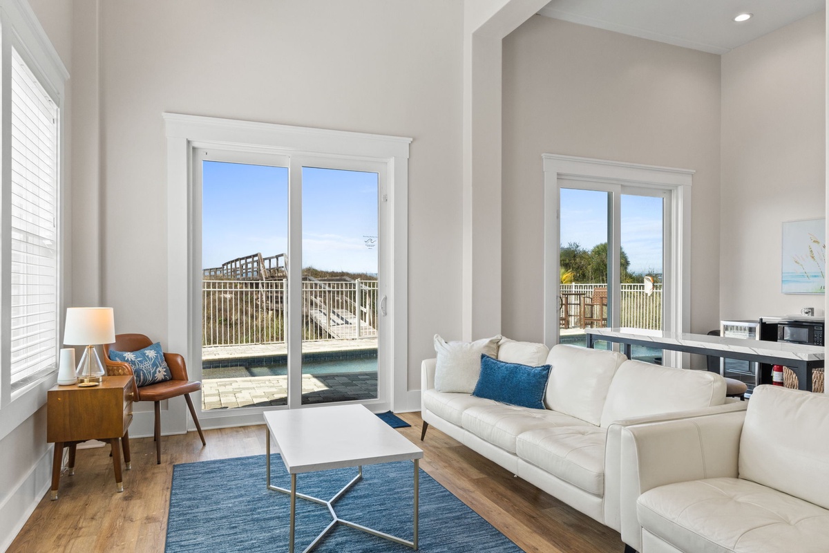 Relax in your bright living room with stunning pool and ocean views through floor-to-ceiling windows—perfect for unwinding after beach days.