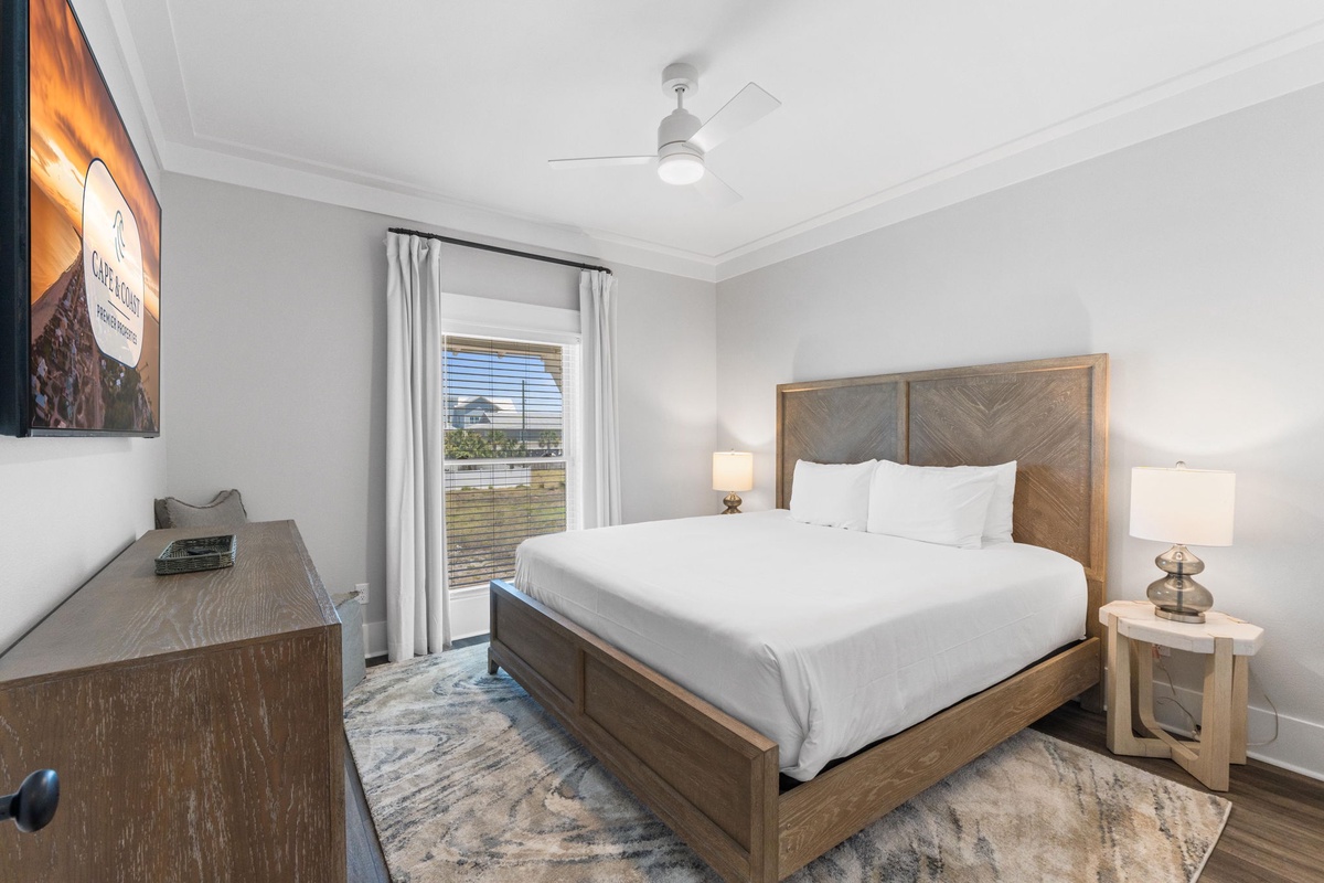 Your peaceful retreat awaits with a luxurious bed dressed in crisp white linens, soft lighting, and a ceiling fan to keep you comfortable throughout your stay.