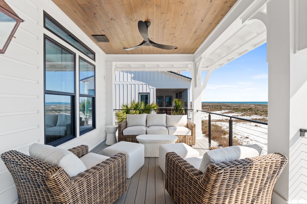Relax in this elegant covered terrace with plush wicker seating and stunning coastal views stretching to the horizon.