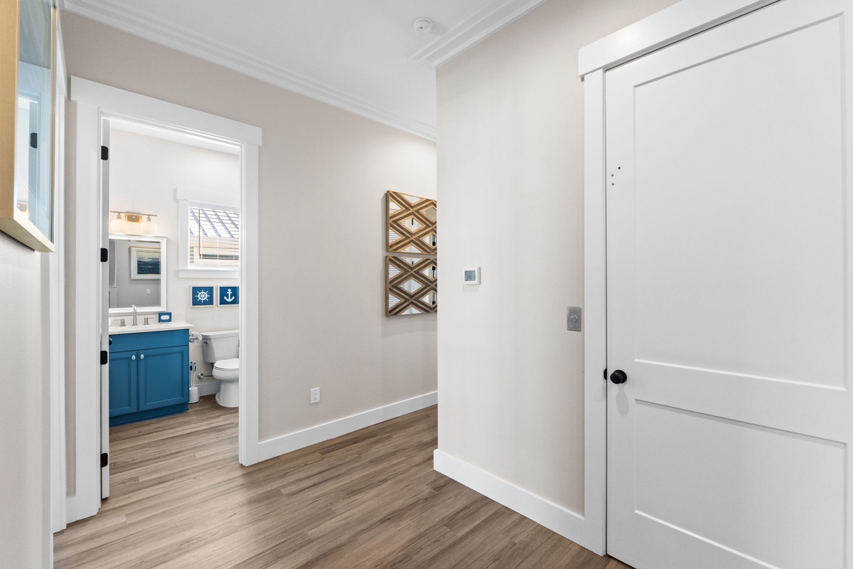 Step into your private hallway where warm wood floors guide you to your stylish bathroom with cheerful blue vanity.