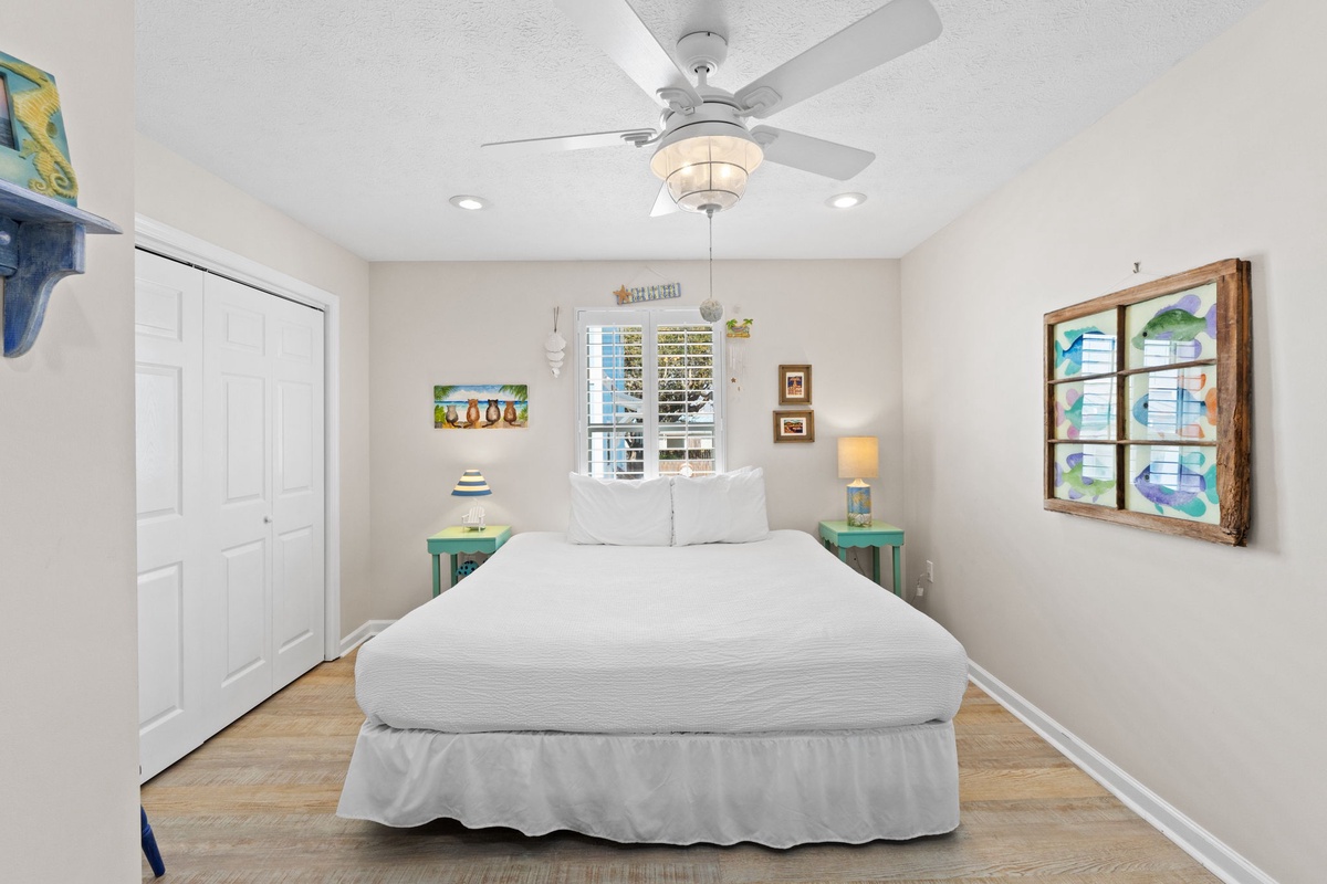 Drift off in your coastal-inspired bedroom with crisp linens, gentle ceiling fan, and cheerful artwork creating the perfect beachside retreat.