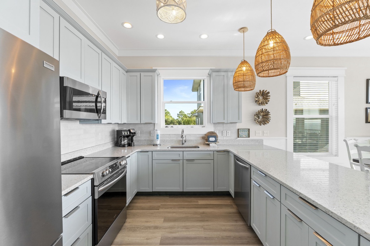 Whip up your favorite meals in this bright, modern kitchen with sleek countertops, stainless appliances, and charming pendant lights.