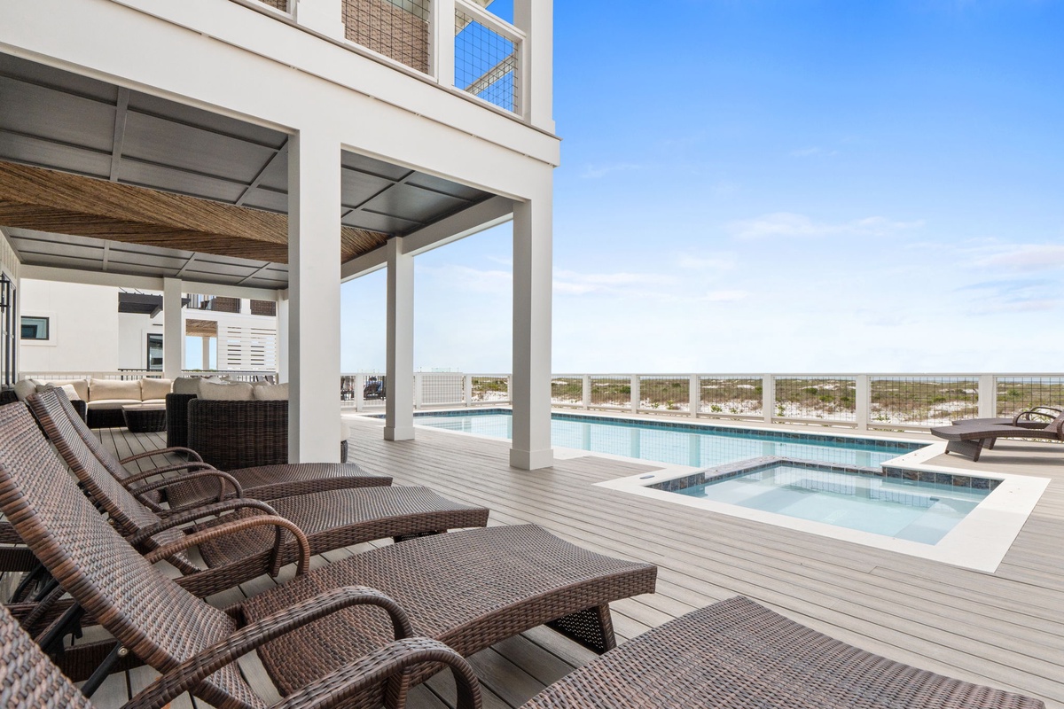 A rooftop oasis with pool, hot tub, and lounge chairs offering sweeping beachfront views under open skies—your perfect escape to unwind and soak up the sun.